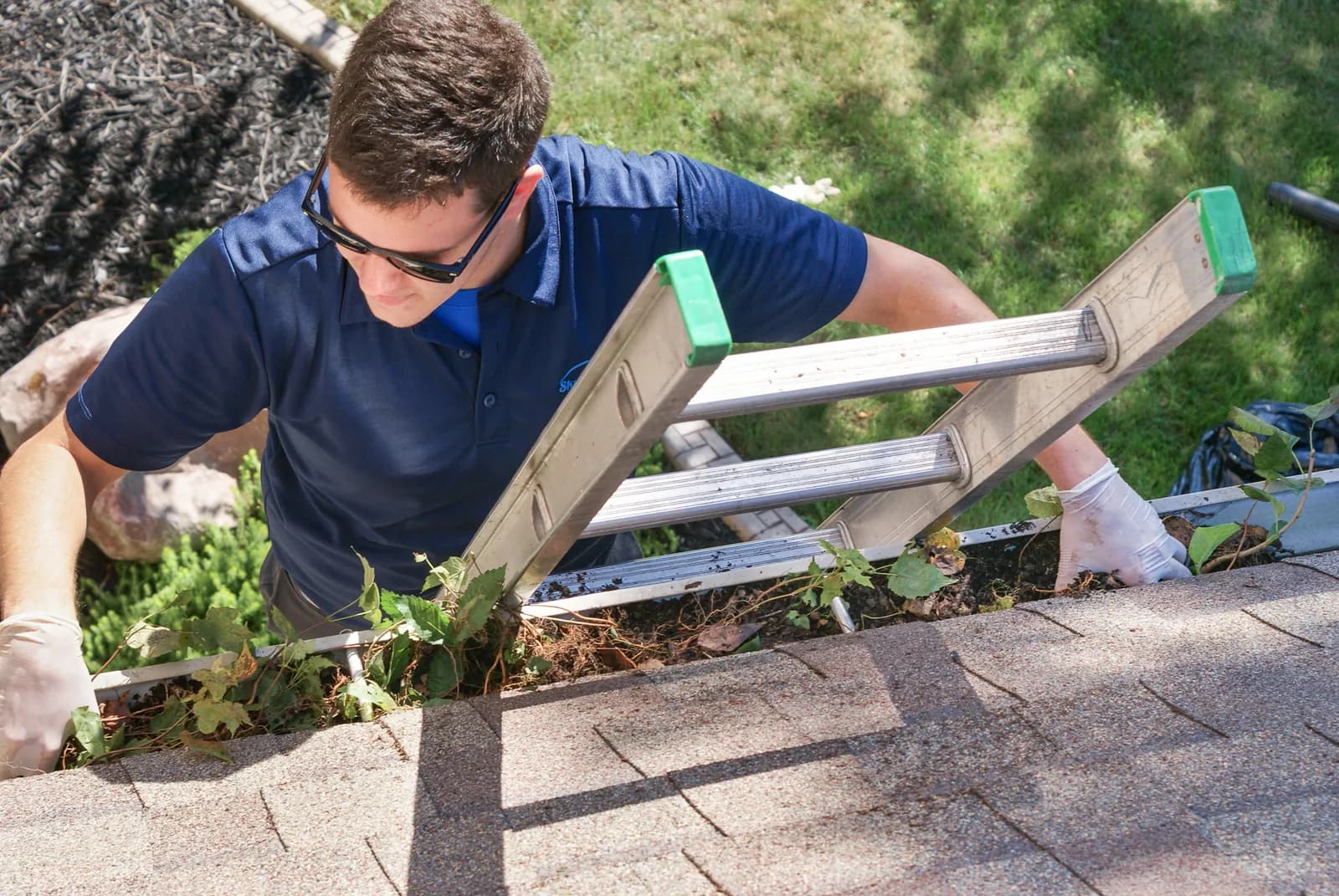 Overhead view of technician cleaning a residential gutter