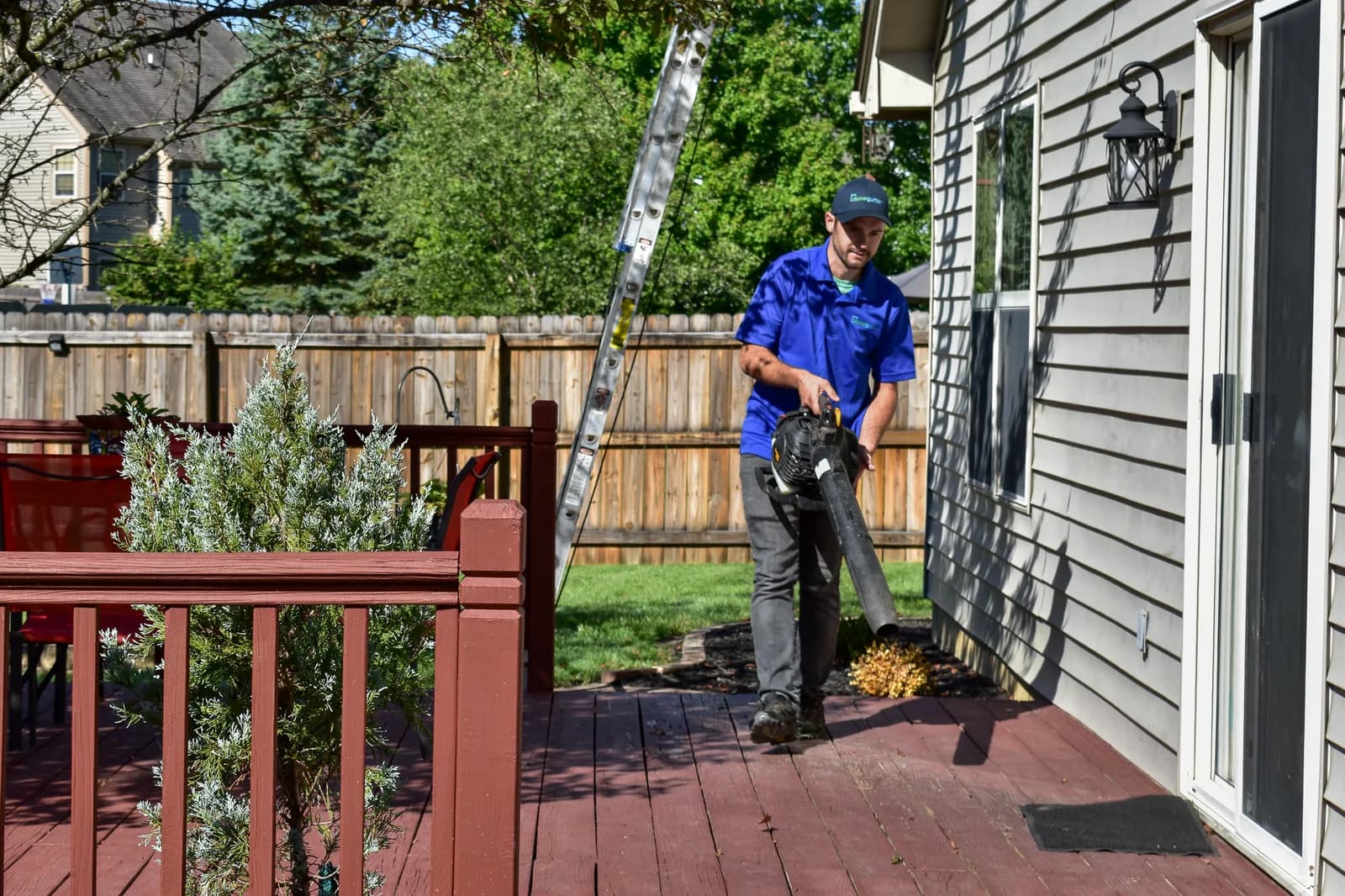 Worker using a blower on a clean patio after gutter cleaning