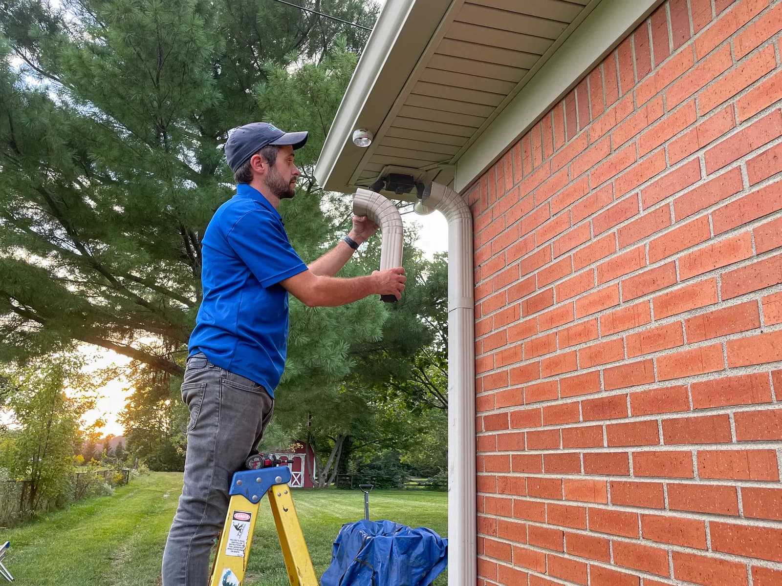 Technician disassembling a downspout at the top of a gutter run