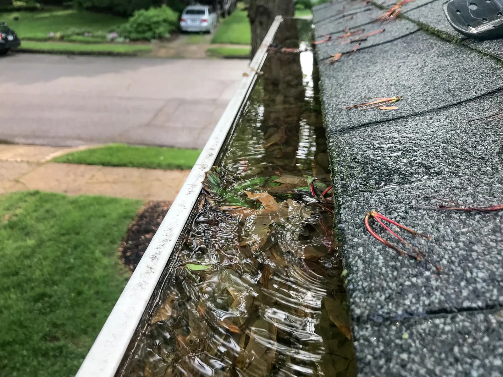 Gutter filled to the top with standing water and a ripple of a drop is seen